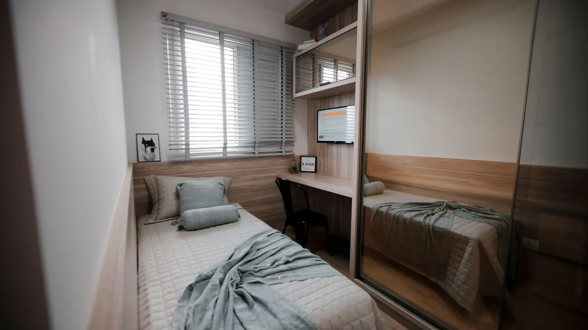 Compact bedroom with monochromatic color scheme, mirrors and clever storage maximizing a small space