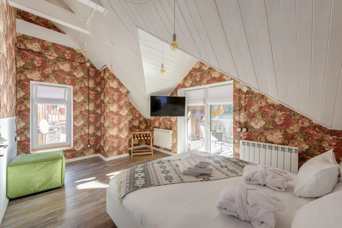 Finished attic living space with exposed beams, built-in shelving, cozy reading nook and natural wood flooring