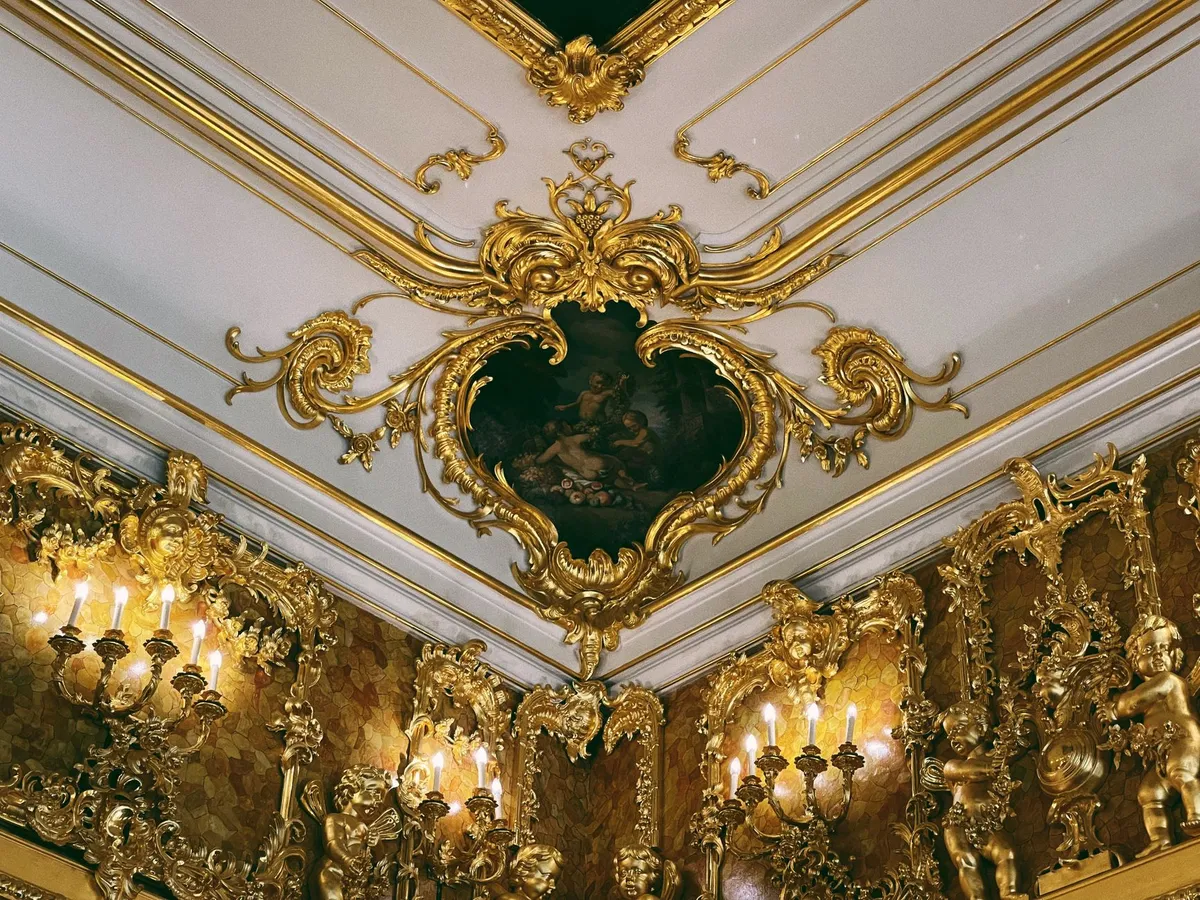 Baroque luxury interior showing ornate ceiling medallion, parquet floor, gilded furniture and dramatic drapery