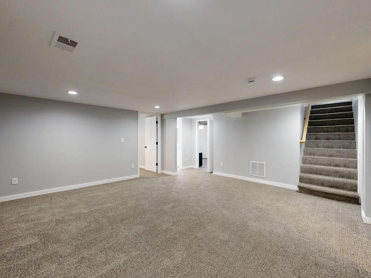 Modern finished basement bedroom with egress window built-in storage and warm lighting