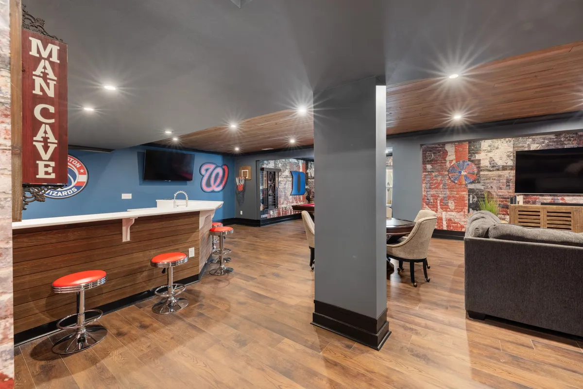 Finished basement home theater with tiered seating, large screen and accent lighting