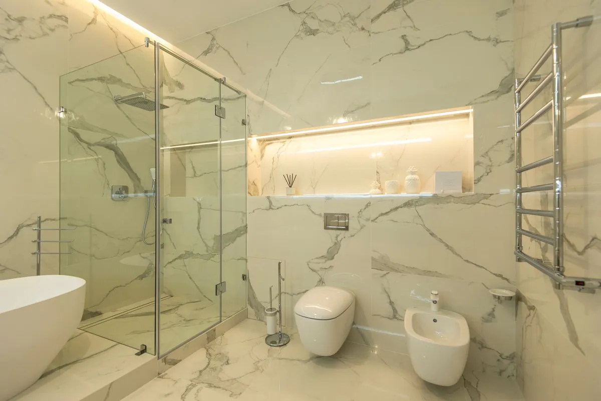 Renovated bathroom with warm stone, floating vanity, rainfall shower, and radiant floor