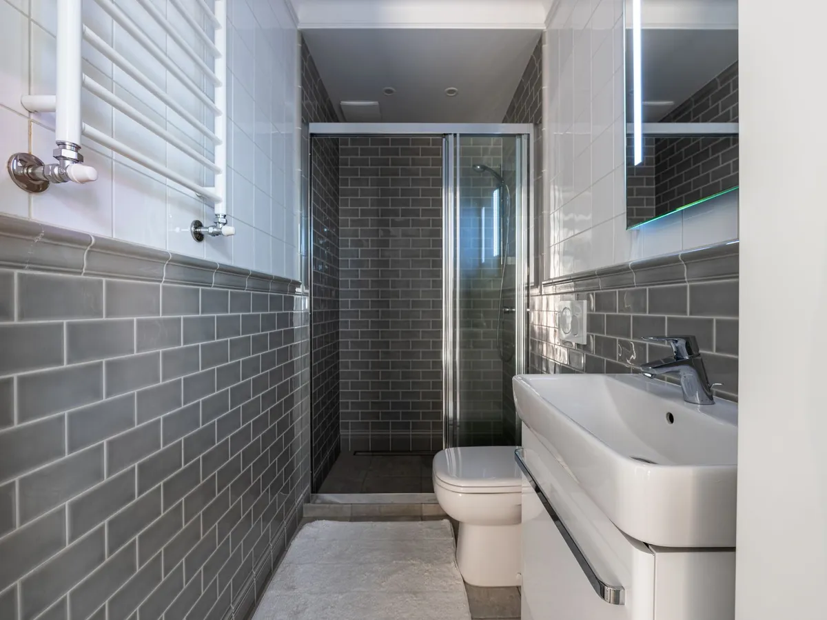 Transformed bathroom on a budget showing before and after with new tile vanity lighting and fixtures for under $4000