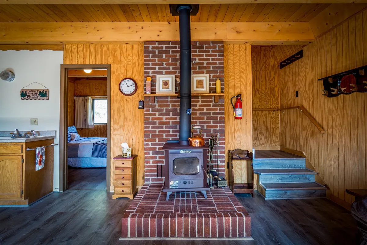 Cabin living room with stone fireplace floor-to-ceiling reclaimed wood walls and leather seating