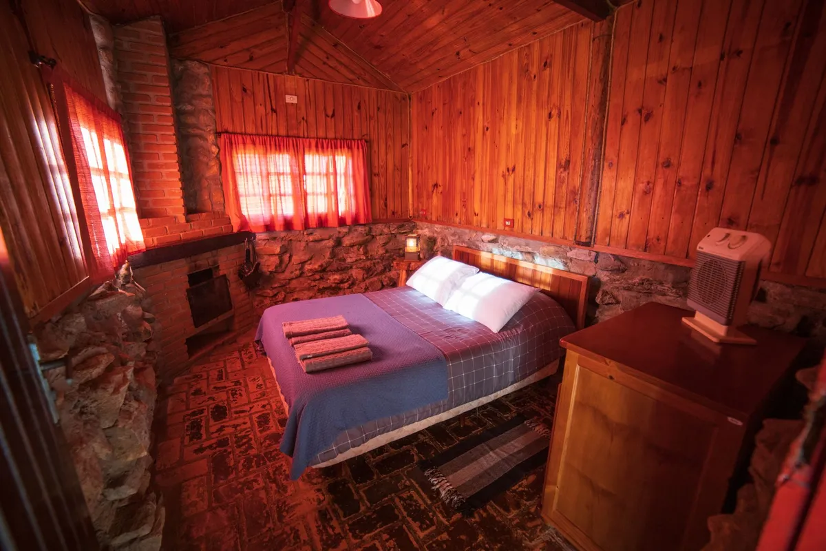 Cabin bedroom with plaid wool bedding exposed beam ceiling and antler wall sconces
