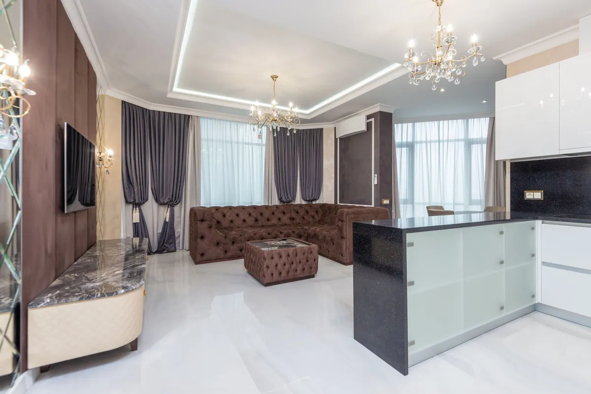 Contemporary luxury dining room with statement chandelier, stone dining table, and linen chairs
