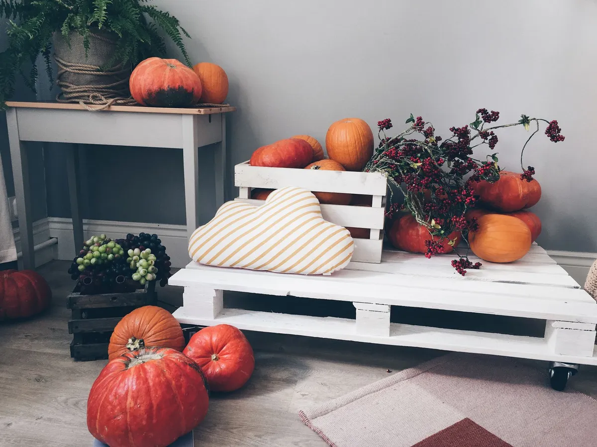 Cozy fall interior with warm candle light, blankets and autumn-toned accessories