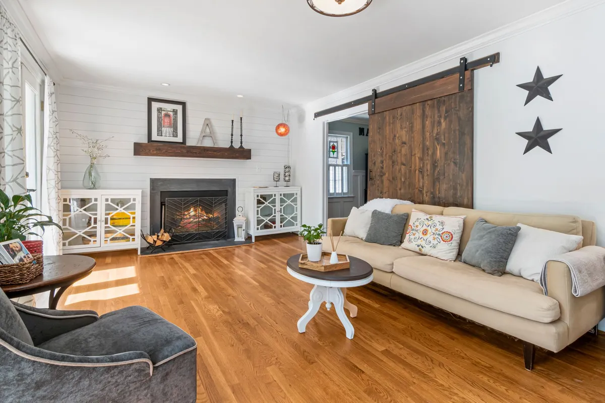 Farmhouse living room with exposed wood beams, white walls, and layered warm neutrals