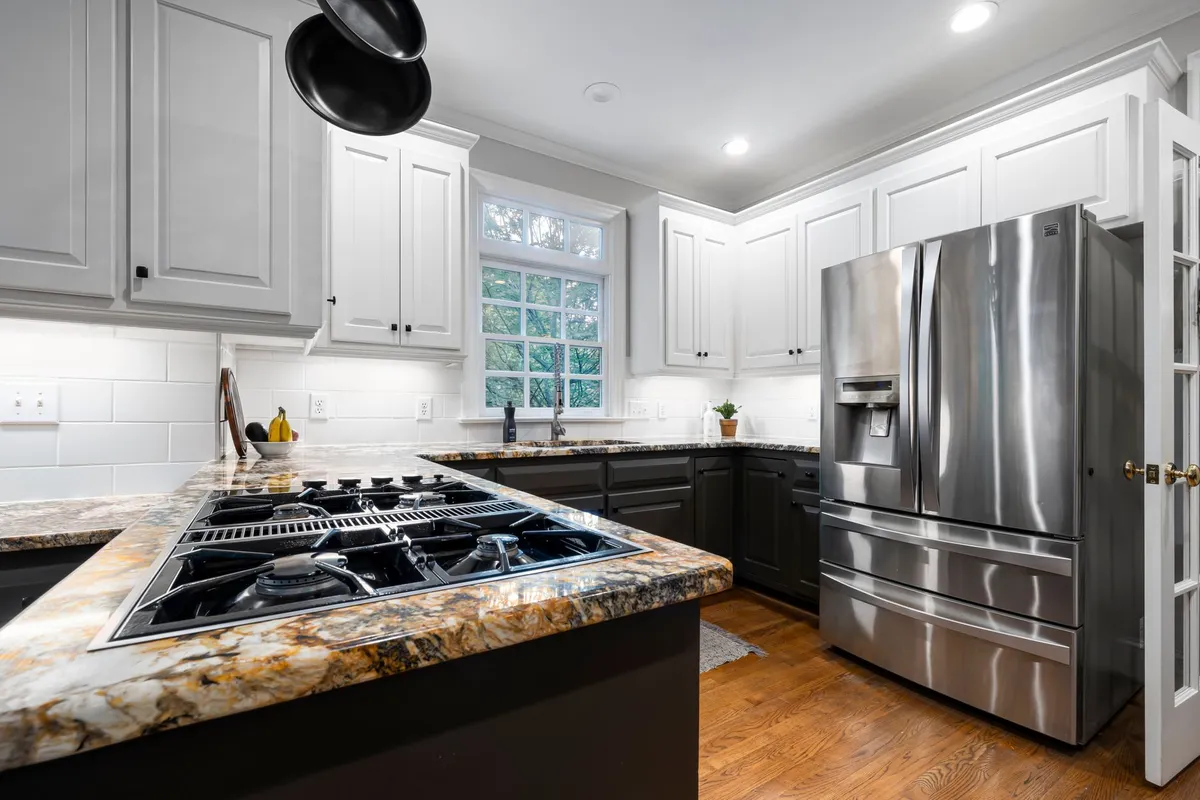 Updated kitchen with painted cabinets, modern pendant lighting, and tile backsplash