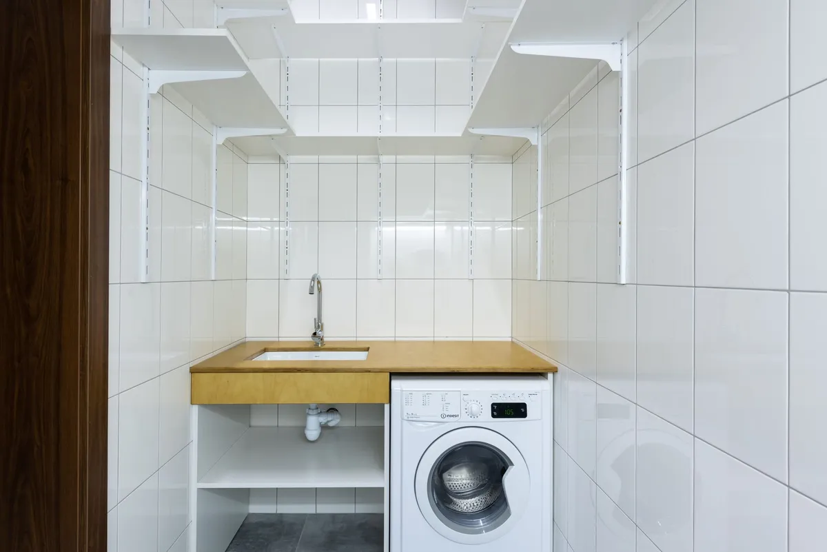 Organized laundry room with sorting station, upper cabinets, and utility sink