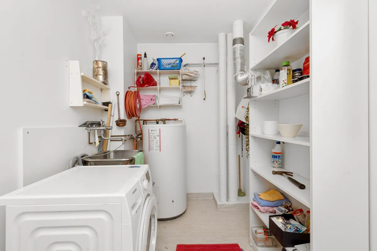 Cheerful laundry room with bold wallpaper, white cabinets, and organized open shelving