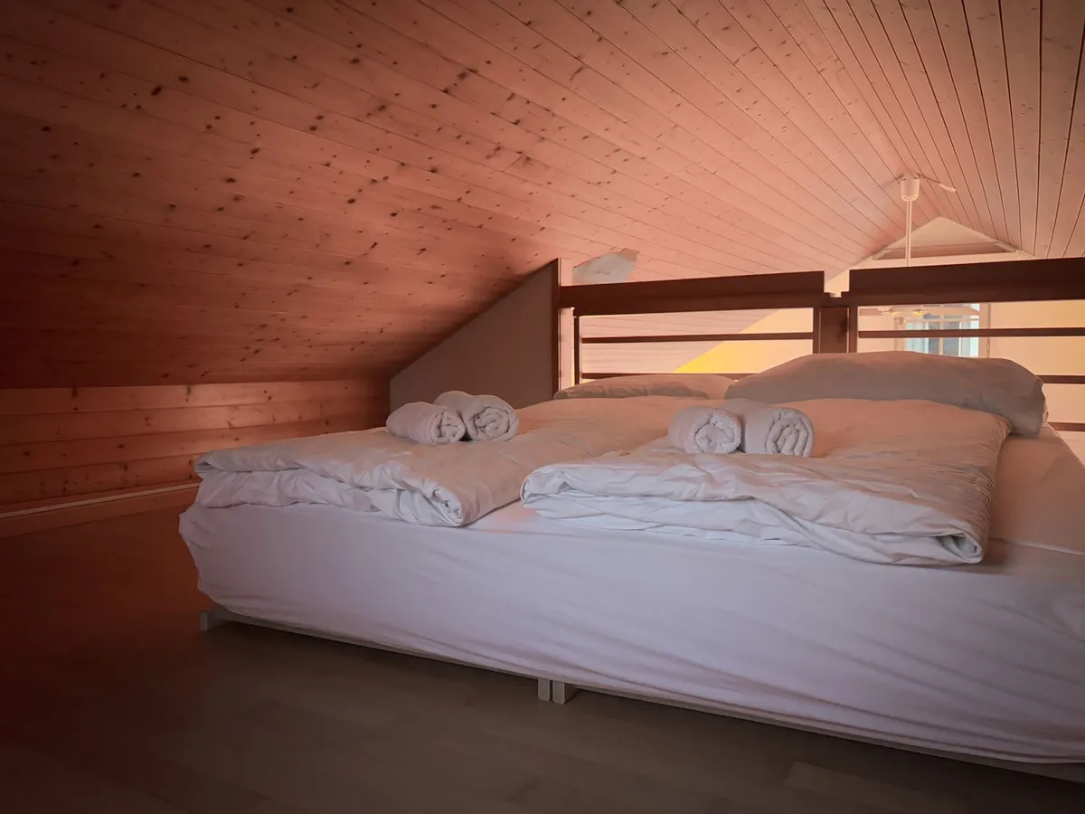 Loft conversion bedroom with velux windows, white walls, and exposed wooden beams