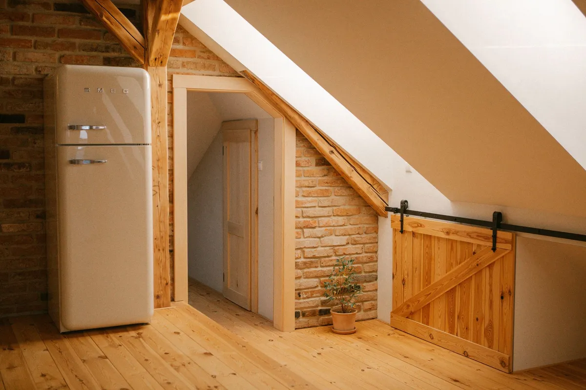Converted attic home office with roof windows, built-in desk, and wood ceiling beams