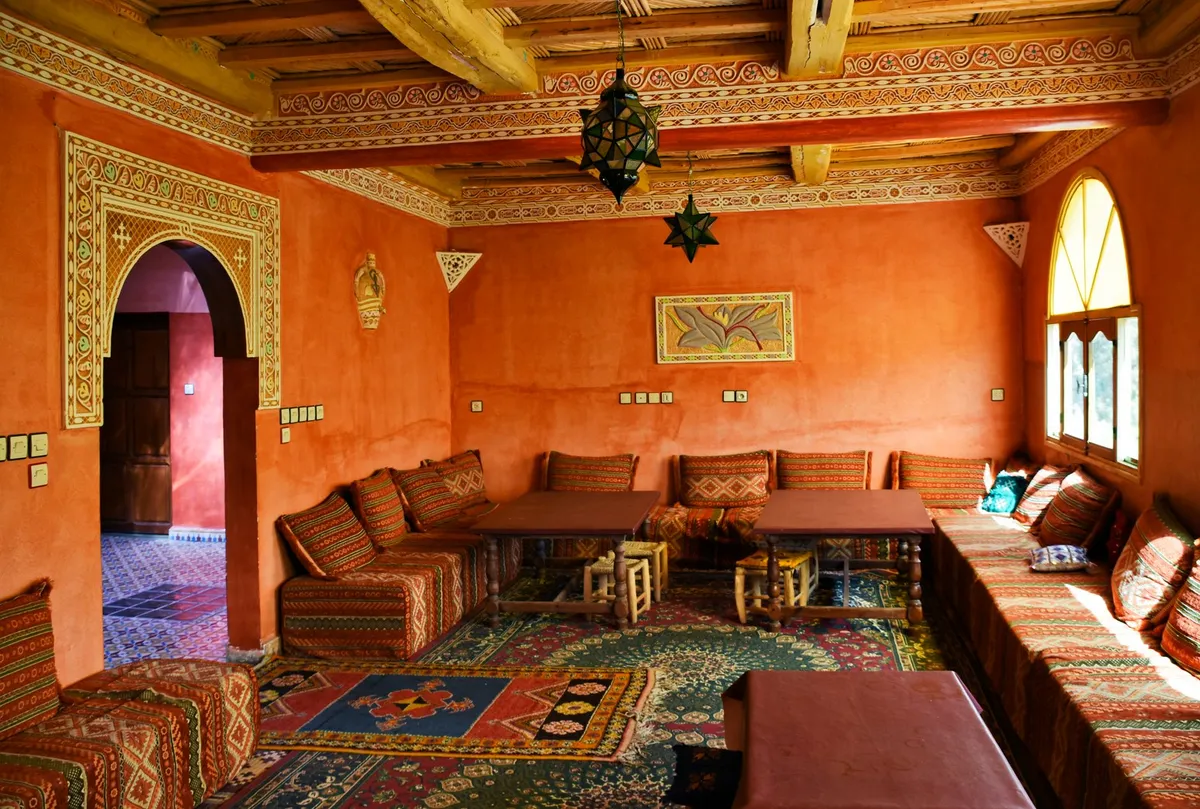 Moroccan lanterns casting geometric shadow patterns on walls in a warmly lit interior with colorful cushions and textiles