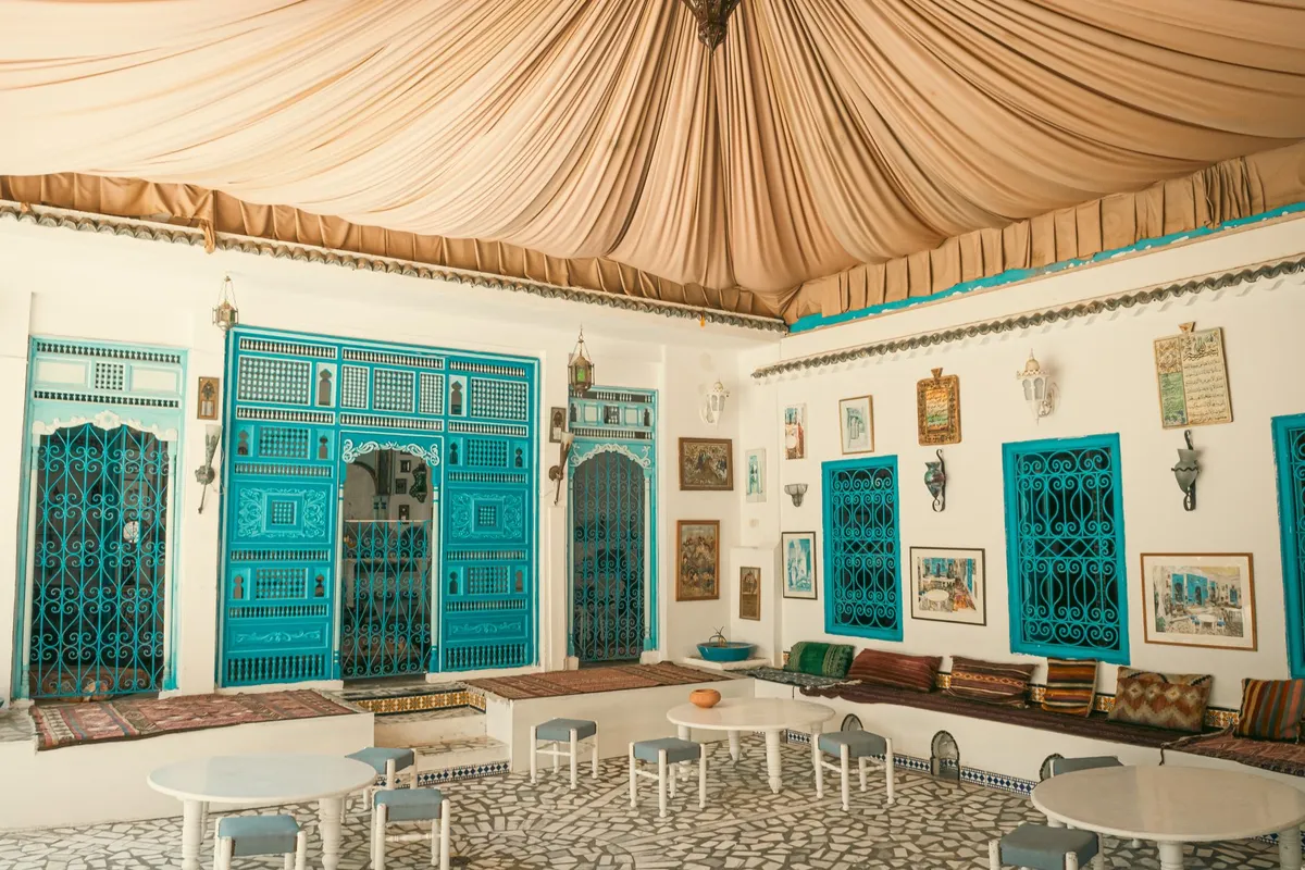 Moroccan-inspired bedroom with colorful patterned cushions, brass lantern, carved wooden details and warm terracotta tones