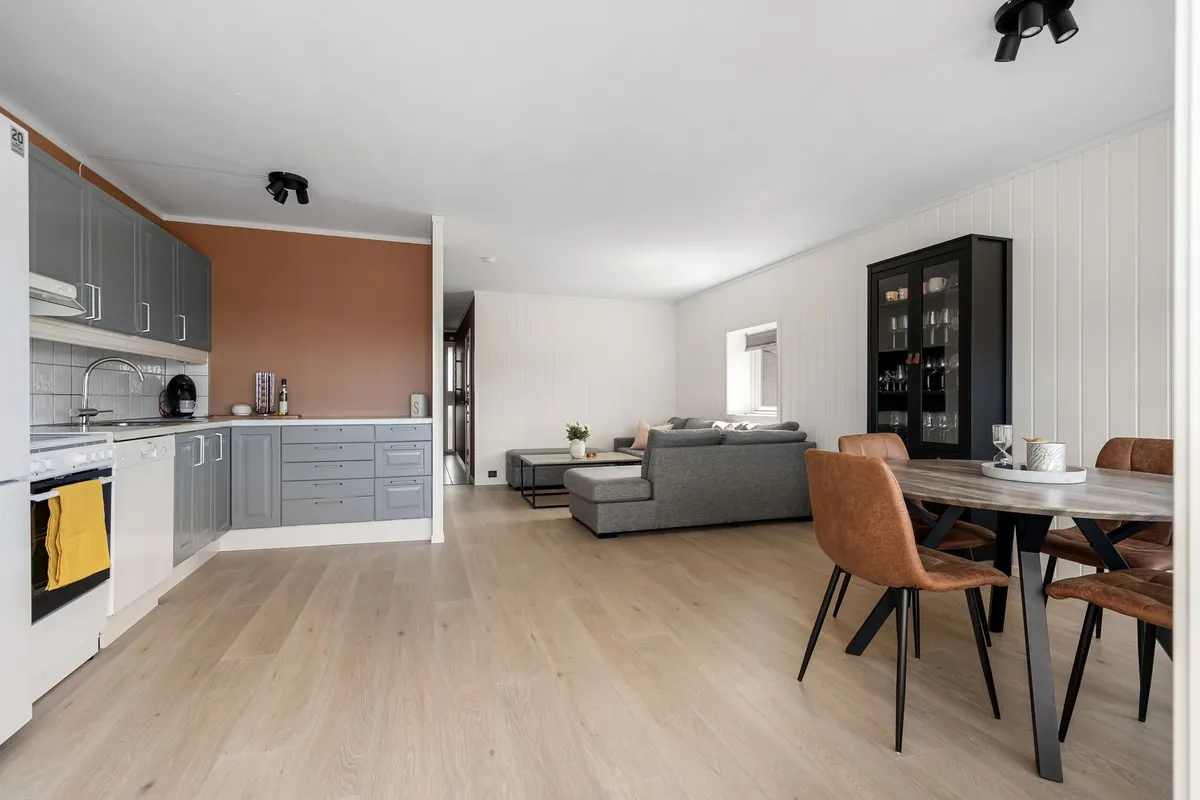 Open plan kitchen dining living area with structural beam and continuous hardwood flooring