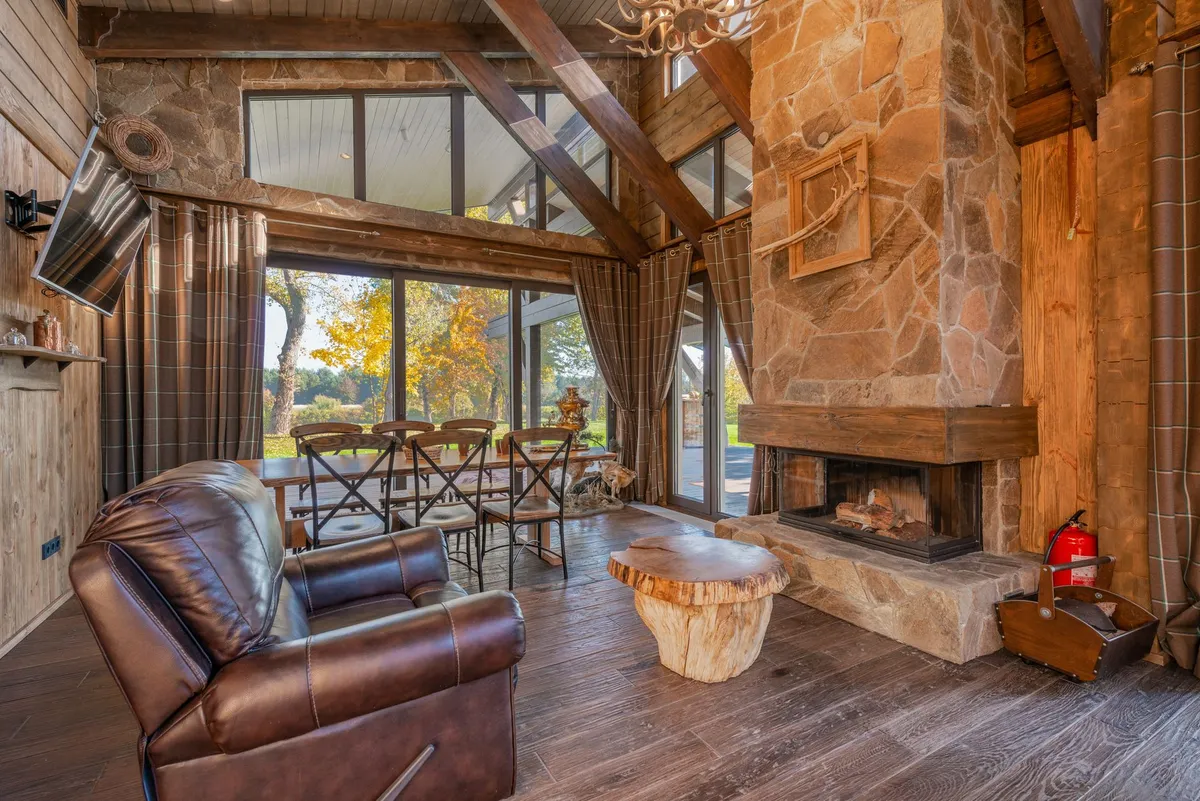 Rustic interior living room featuring exposed wooden beams, stone fireplace, and natural material textures