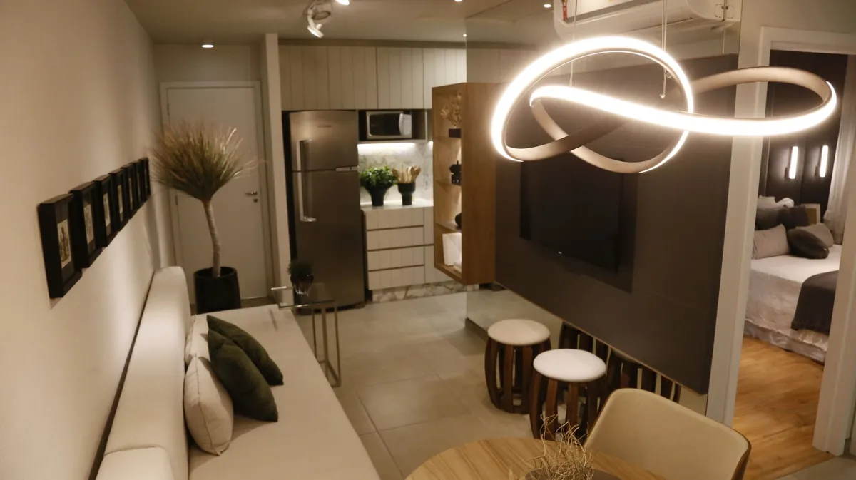 Open studio apartment zoned with a floating sofa as room divider, coordinating rugs, and layered lamp lighting