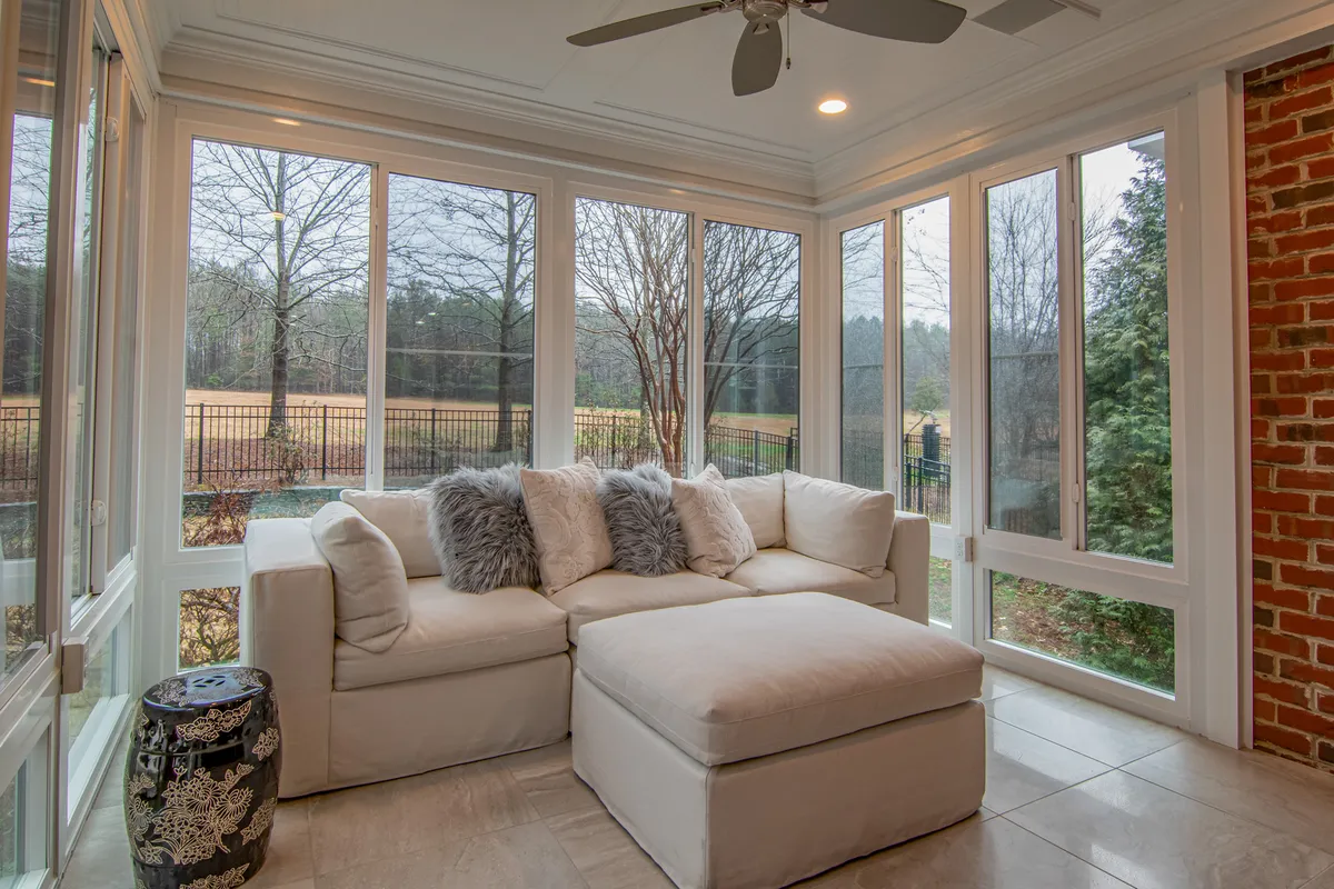 Bright sunroom with floor-to-ceiling windows and comfortable seating arrangement