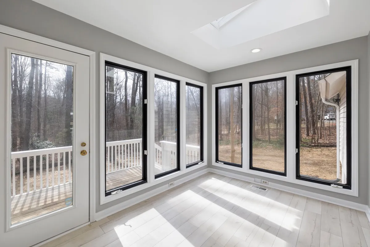 Four-season sunroom with comfortable seating, plants, and view of garden